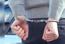 Image shows a person with their arms handcuffed behind their back