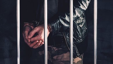 Handcuffed man behind prison bars (Representative Image)