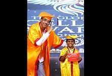 Principal in Pushpa pose at convocation, dressed in academic gown, celebrating achievement.