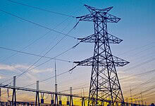 High voltage transmission tower with power lines in Telangana at sunset.
