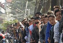 Crowd of young voters participating in Nepal election campaign, many wearing masks and holding campa.