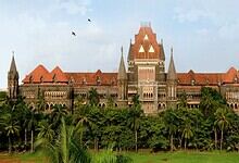 Historic Maharashtra government building with lush greenery and palm trees in front.