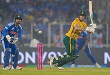 A cricket player in yellow batting for South Africa during a match against India, with the wicketkeeper a.