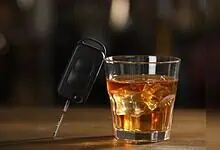 Image shows a car key and a glass of whiskey, emphasizing the crackdown on drunk driving by Hyderabad traffic police.