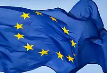EU flag with yellow stars on a blue background, symbolising unity and cooperation.