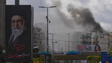 A portrait of Iran's late Supreme Leader Ayatollah Ali Khamenei, left, is seen, as smoke rises following an Israeli airstrike in Dahiyeh, Beirut's southern suburbs, Lebanon