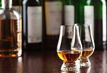 Alcoholic drinks served in glasses on a bar counter with bottles behind.