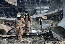 Soldiers inspecting destruction after explosion in urban area.