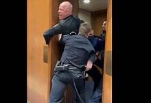 A former US Marine is escorted by police while protesting