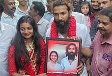 A man holding a framed photo of Monalisa Bhosle, surrounded by friends and family during her wedding at T.