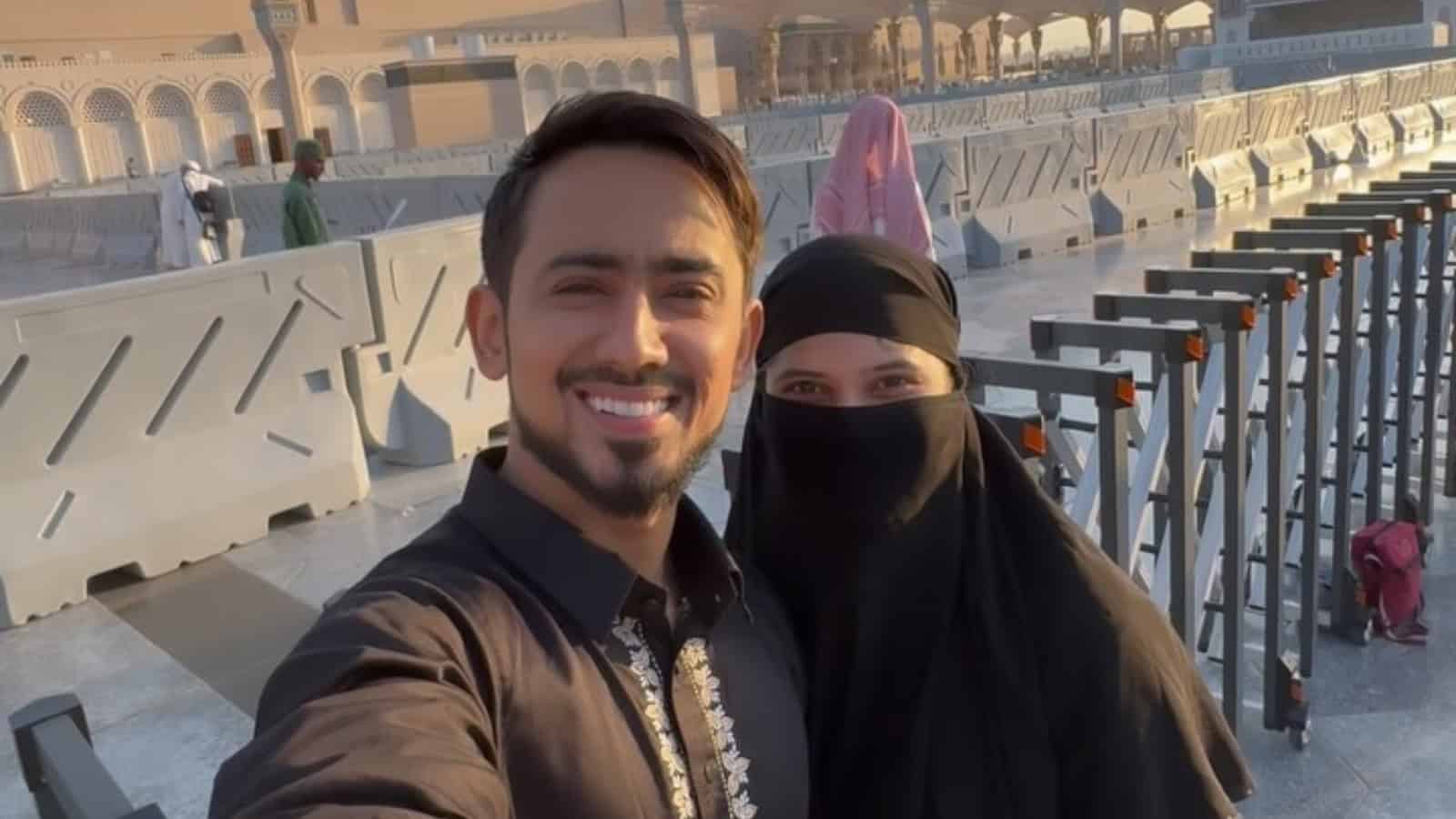 Happy couple taking a selfie at a mosque, celebrating conversion to Islam before marriage.