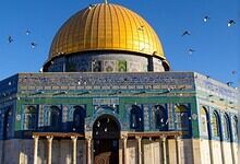 View of Al-Aqsa Mosque with golden dome and blue tile exterior in Jerusalem.