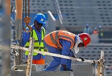 Workers on construction sites in Oman, wearing safety gear and helmets, involved in building infrastructu.