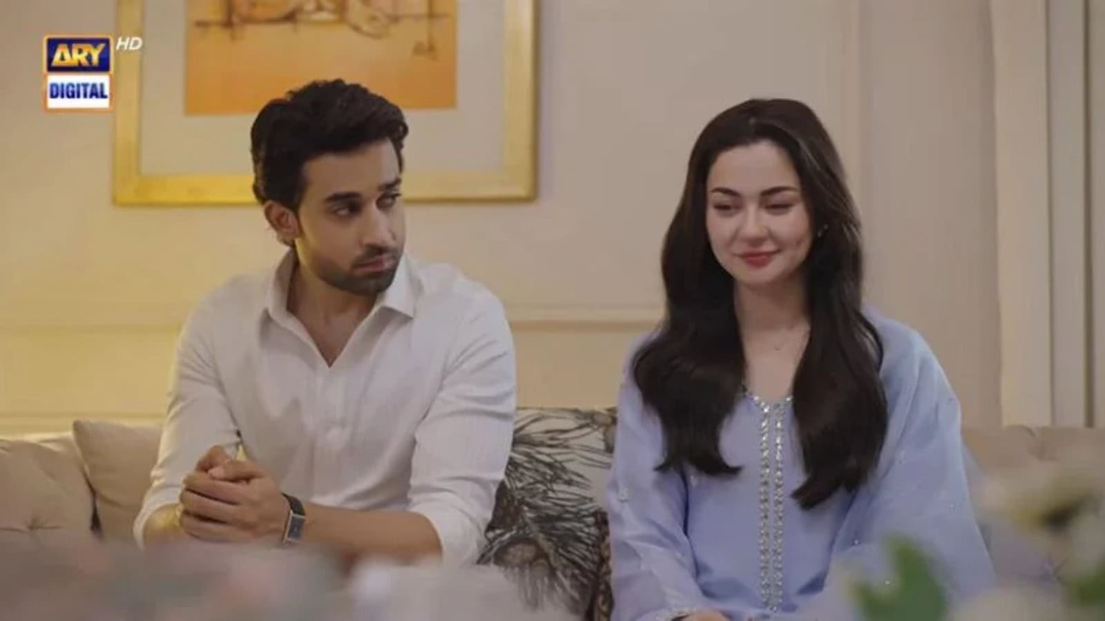 Two characters from Meri Zindagi Hai Tu episode 32 sitting on a sofa, smiling, in a cozy indoor setting.