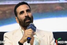 Akshay Kumar speaking into a microphone at a film event, discussing his role in Vanga and Dhar films.