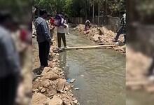 Locals crossing a nala in Banjara Hills using wooden planks during flood conditions.