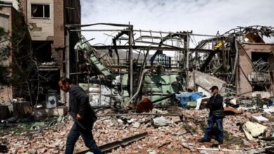 People walk past debris and inspect damage at a destroyed research building at Shahid Beheshti University in Tehran following a strike on April 4, 2026.