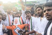 Protesters holding banners and a portrait of Narendra Modi during a rally in India.