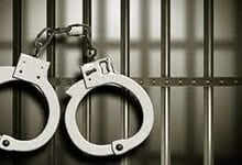 Handcuffs hanging on prison bars symbolising law enforcement and criminal justice.