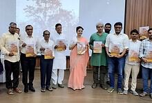 A woman in a peach saree and men in formal attire holding copies of The Siasat Daily at a book launch eve.