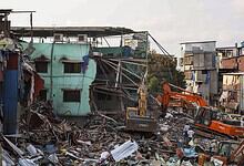 Urban building collapse with rescue operations and heavy machinery in a densely populated area.
