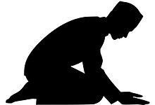 A man kneeling in prayer silhouette, symbolising devotion and spirituality.