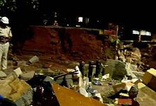 Construction site with workers and debris, safety helmets, and scattered materials in an outdoor environm.