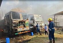 Burnt vehicles after fire in open field used for parking in Hyderabad, with firefighters working to contr.