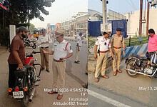 Motorcycle police officers interacting with civilians on a busy street in Tirumalagiri, Hyderabad, India.