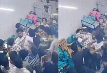 A crowded scene at an indoor event with people engaged in a physical altercation or scuffle.