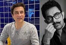 Faissal Khan in casual attire, smiling, with a blue tiled background.