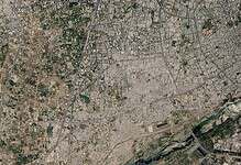 Satellite image of a city with a river running through it, showing urban and green areas.