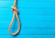 Rope hanging against a bright blue wooden wall, symbolising a distressing scene.