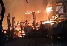 Fire engulfing industrial equipment at night, with intense flames and smoke rising, causing significant d.
