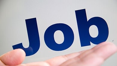 Close-up of a hand holding a sign with the word 'Job' in bold blue letters.