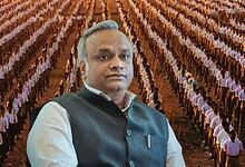 Man in formal attire standing in front of a large crowd of people in a field.