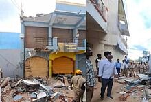 Collapsed commercial building in Raichur with rescue workers and onlookers present.