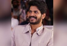 Actor Akhil smiling in a beige suit at a public event.