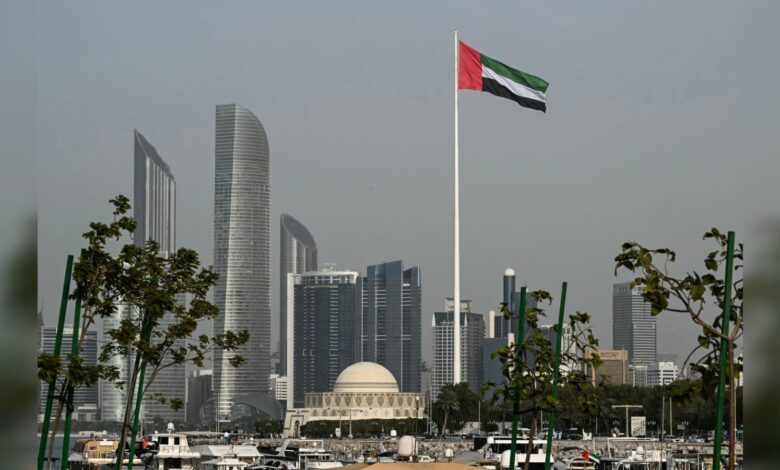 UAE flag flying over the Abu Dhabi skyline on a clear day.