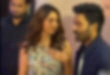 A celebrity couple engaged in conversation at a public event, with a blurred background.