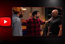 Three men having a discussion in a room with a Netflix logo in the background.