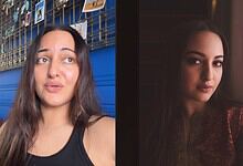 Sonakshi looking thoughtful with a blue background and photos on display behind her.