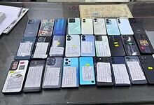Collection of various smartphones displayed on a glass table with notes attached to each device.