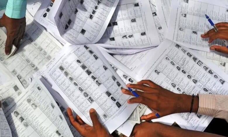 Voters' lists and ballot papers being reviewed and sorted by election officials.