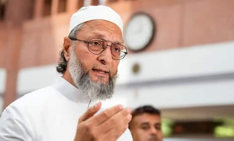Owaisi speaking passionately, wearing white traditional attire and glasses, in a public setting.
