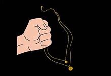 Hand holding a gold chain with a pendant against a black background.