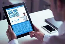 Person holding a tablet displaying online courses related to education and skills development.