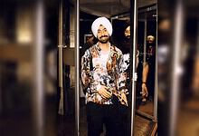 Punjabi singer Diljit Dosanjh in stylish attire at an indoor event in Paris.