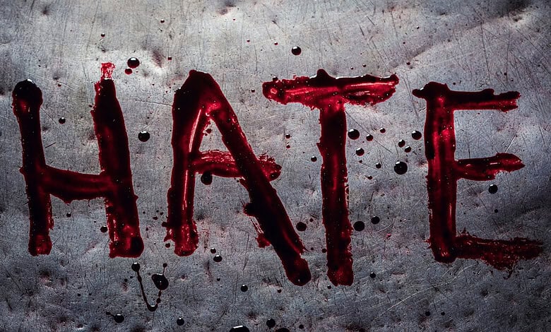 The word 'HATE' written in red blood-like substance on a grey surface.