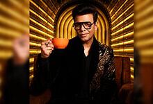 Aamir Khan in stylish black outfit holding an orange cup on Koffee With Karan 9 set.